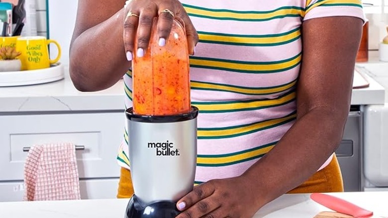 Woman using a bullet blender in her kitchen