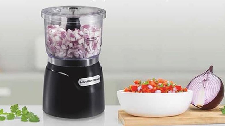 A small electric chopper with diced onions inside