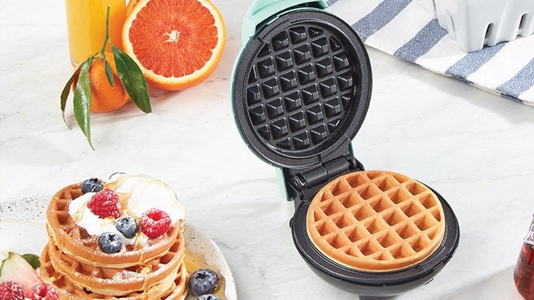 A black waffle maker with a cooked waffle inside