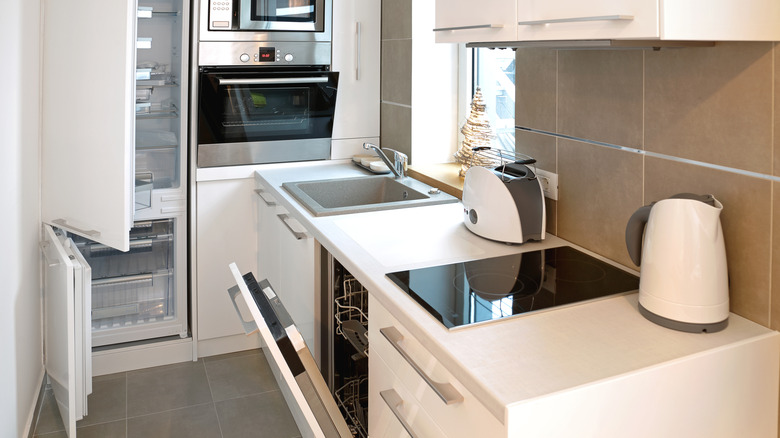 A toaster and kettle on the counter of a small white kitchen