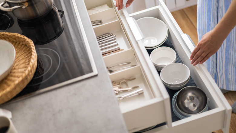 Woman opening drawer of bowls
