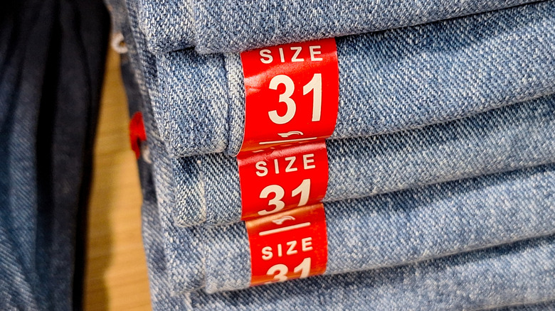 Jeans with stickers on store shelf.