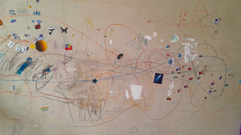 Stickers and scribbles on the painted wall of a home.