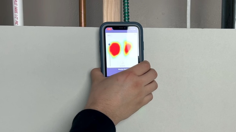 person holding smartphone stud finder app