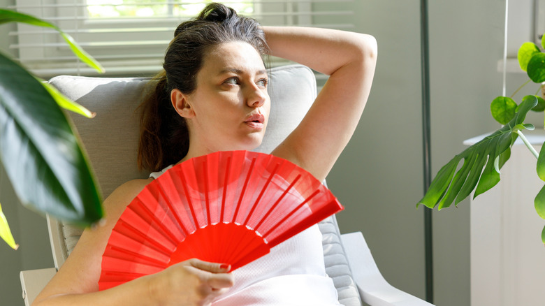 Overheated woman uses a hand fan