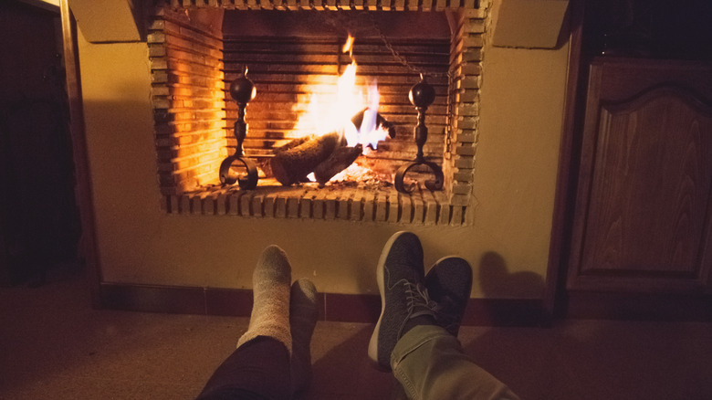Crossed feet of two people lying in front of fire in fireplace