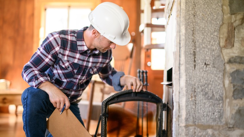 A man in a hard hat conducting a fireplace inspection