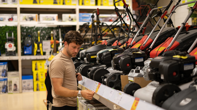 Man choosing a lawn mower in a store
