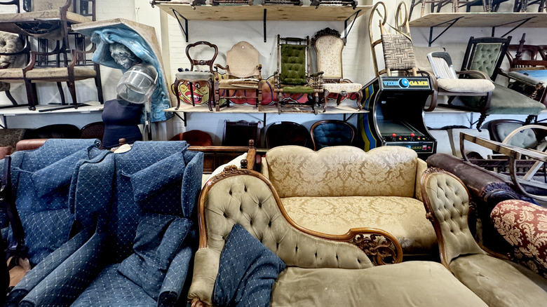 Thrift store furniture section with sofas, chairs, and other items
