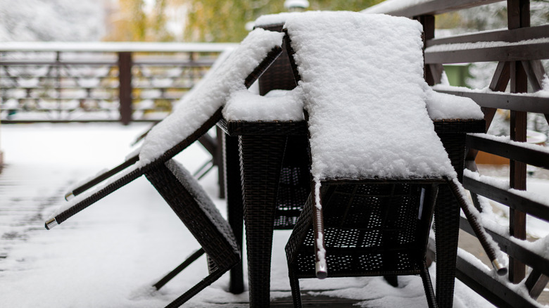 fresh snow covers an outdoor table and chairs