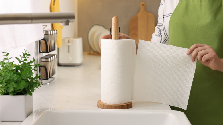 woman pulling paper towel from roll