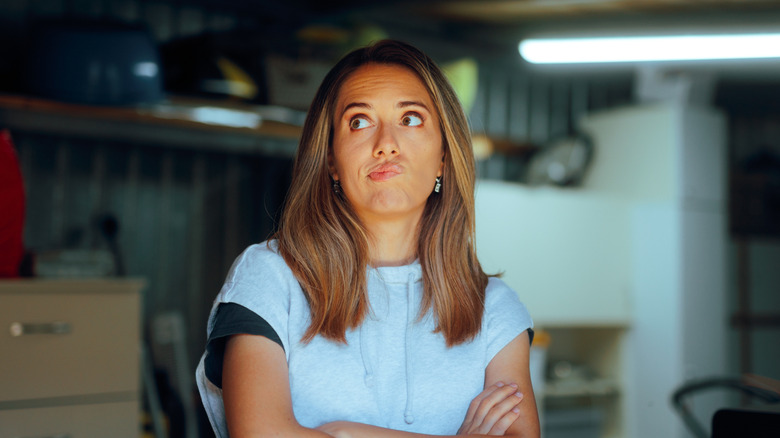 A woman thinking about how to declutter her garage