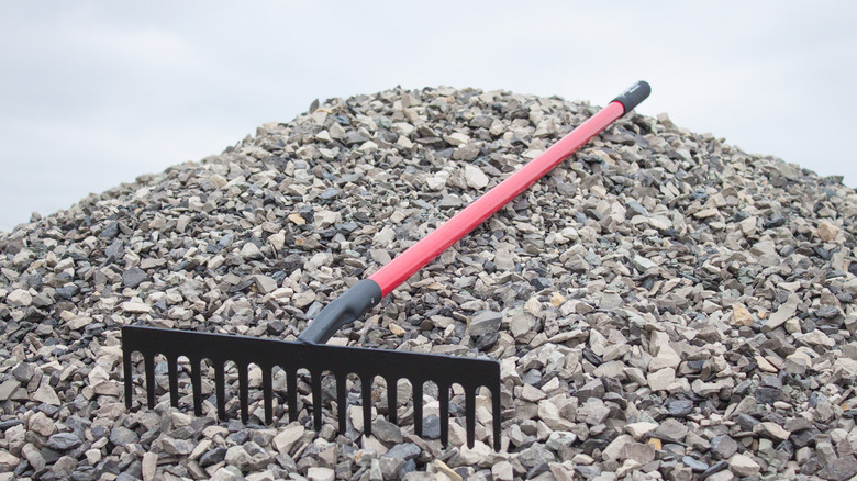 A stone rake sitting on a pile of gravel