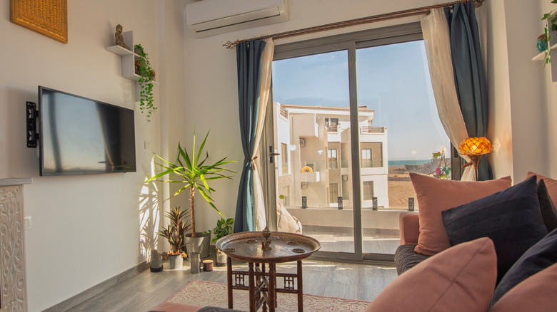 A small living room with sliding glass doors and a neighboring residence visible through the glass doors.