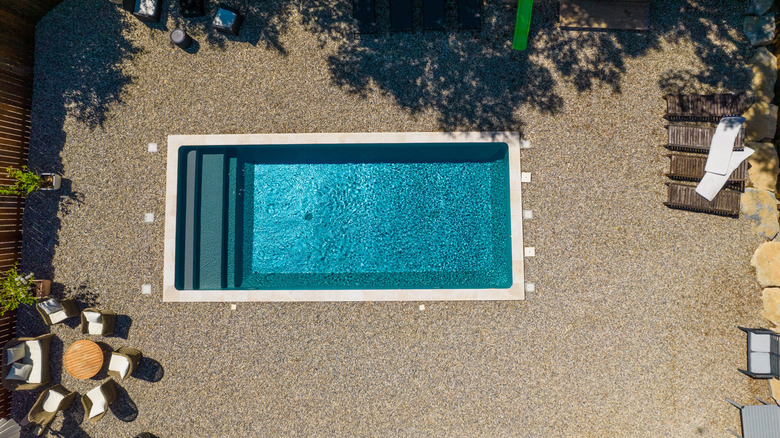 A rectangular swimming pool surrounded by gravel.