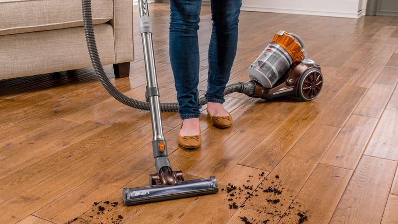 The Bissell vacuum picking up dirt on a hard wood floor