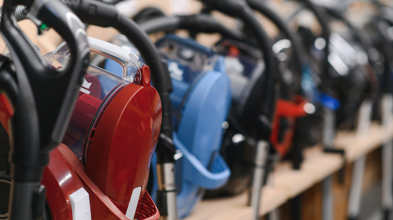 A shot of multiple vacuum cleaners, fading into soft focus at the back.