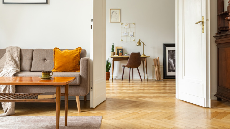 living room and hallway with yellow-toned wood floors and white french doors