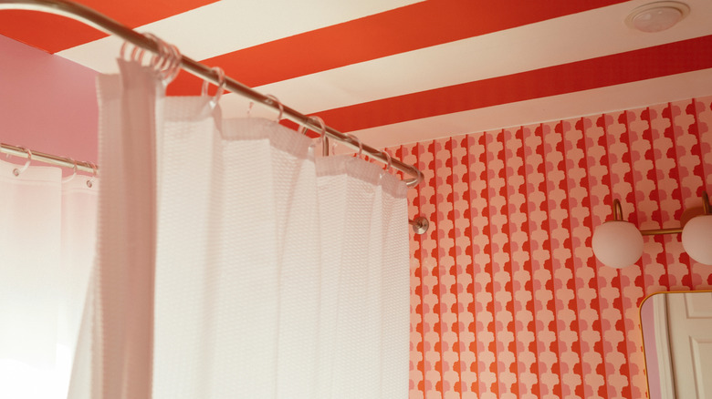 A bathroom with a bright red and white patterned wallpaper on the wall and ceiling