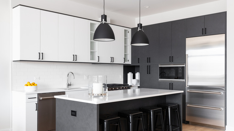 A black and white kitchen uses task lighting, accent lighting, and overhead lighting