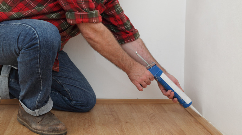 Person caulking baseboards