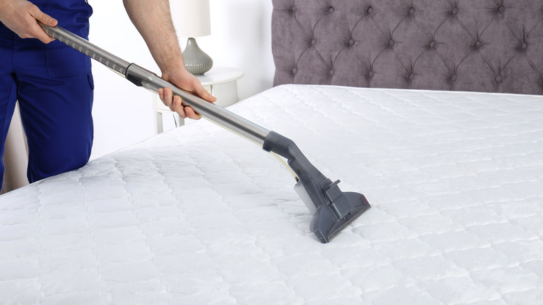 person vacuuming a mattress