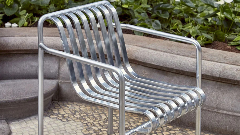 Shiny galvanized outdoor steel chair in a paved area with raised bed in the background
