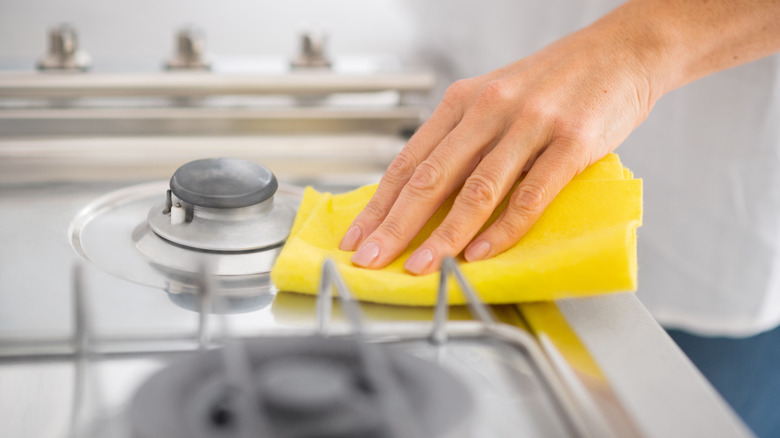 woman cleaning stove with sponge