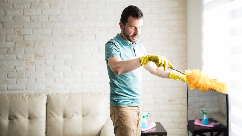 man dusting TV