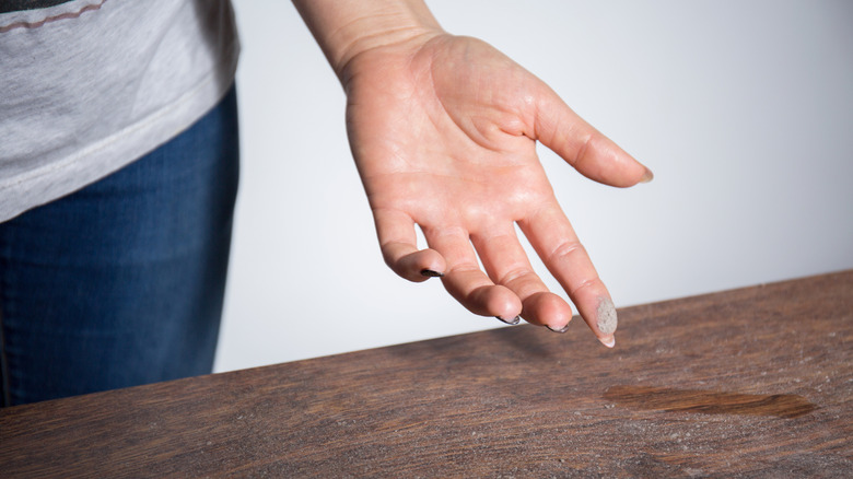 Someone swiping their finger across a dusty table