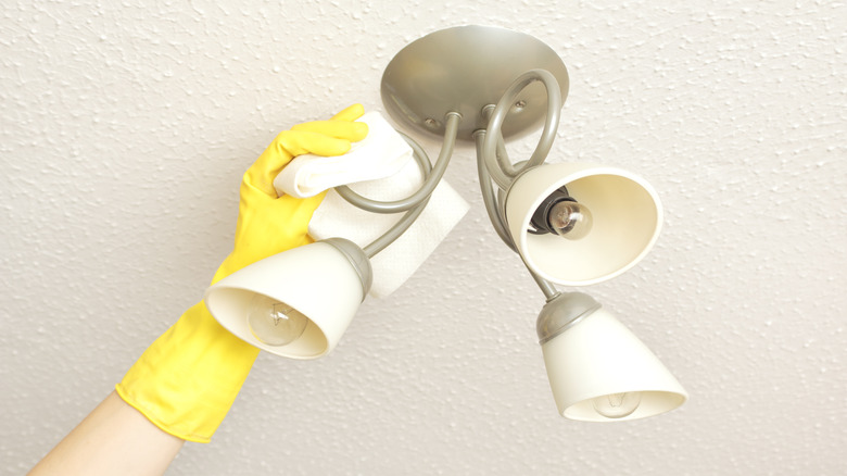 person cleaning ceiling light