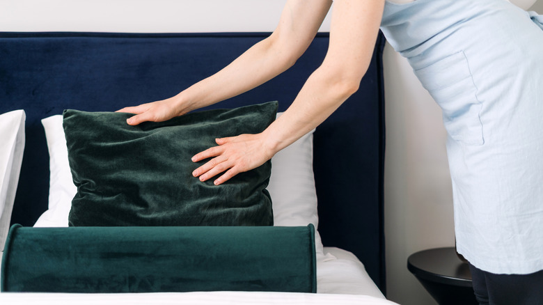 Woman fluffing velvet bed pillow