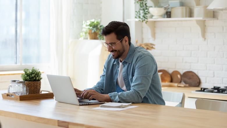 Happy man at laptop in kitchen