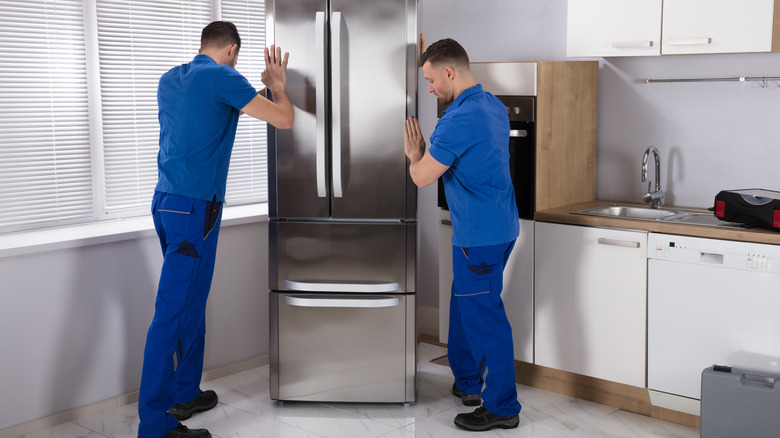 Men moving refrigerator into place