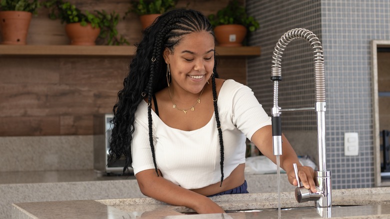 woman running water in sink 