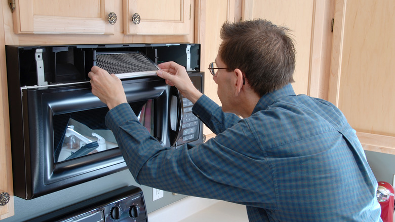 man replacing microwave filter