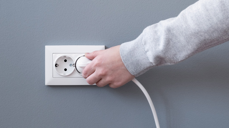 Person plugging in cord outlet