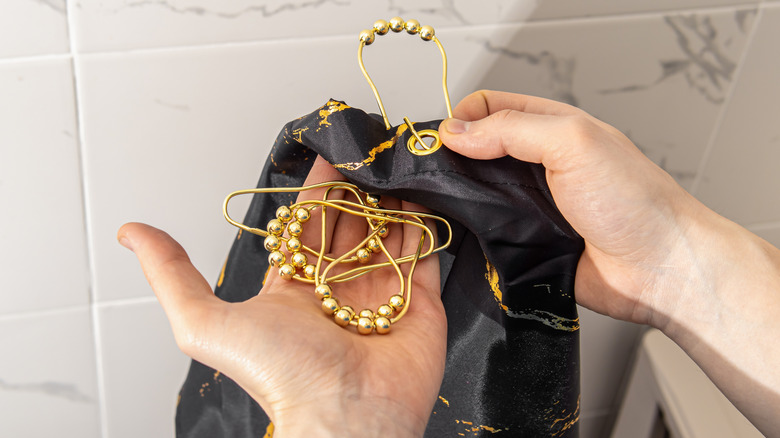 Man holding shower curtain rings and curtain in bathroom