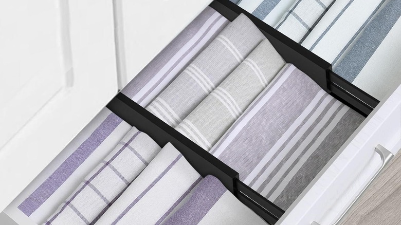 Black drawer dividers are used to separate layers of folded kitchen towels