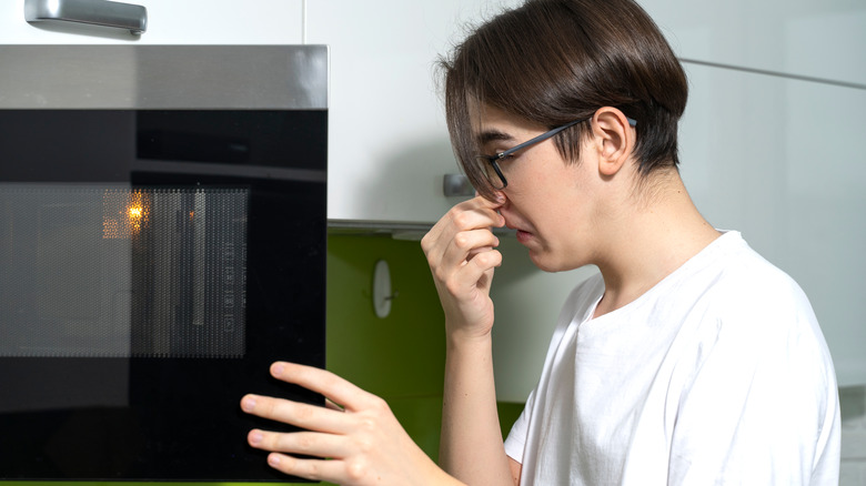 Person plugging nose at microwave
