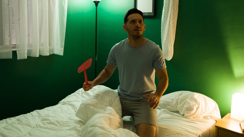 Man chasing bug with swatter