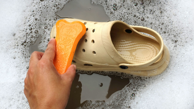 washing a pair of foam clogs in soapy water with sponge