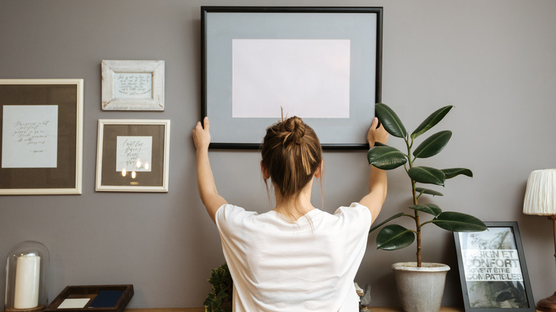 Person hangs art on wall