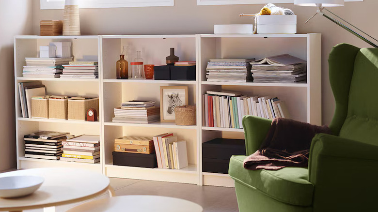 White bookshelf next to green upholstered chair