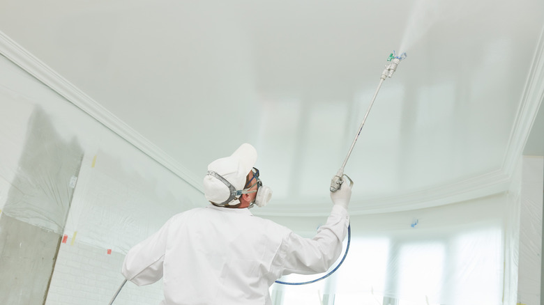 Person using sprayer on ceiling