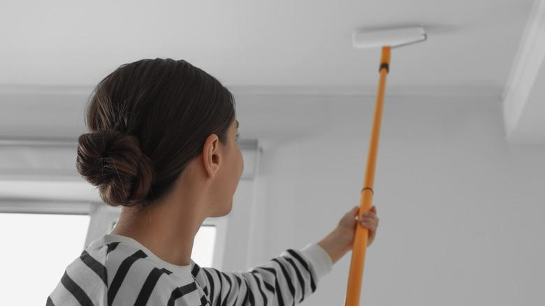 Person painting ceiling in home
