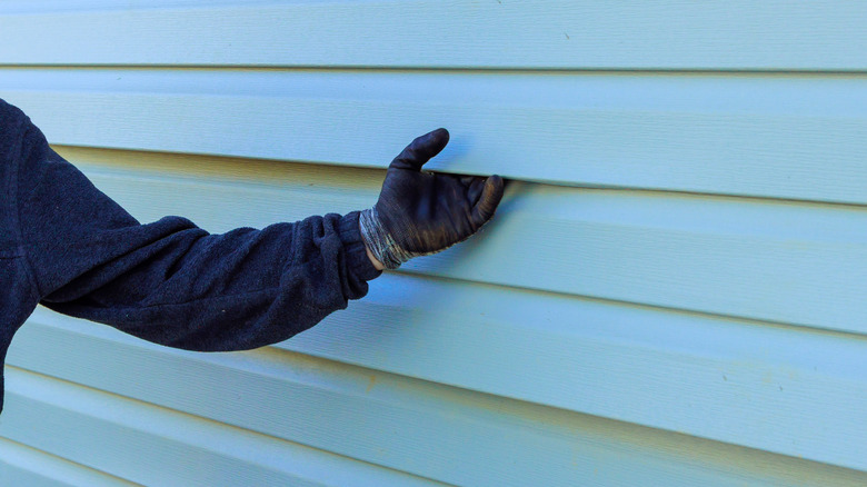 A person inspecting a home's siding
