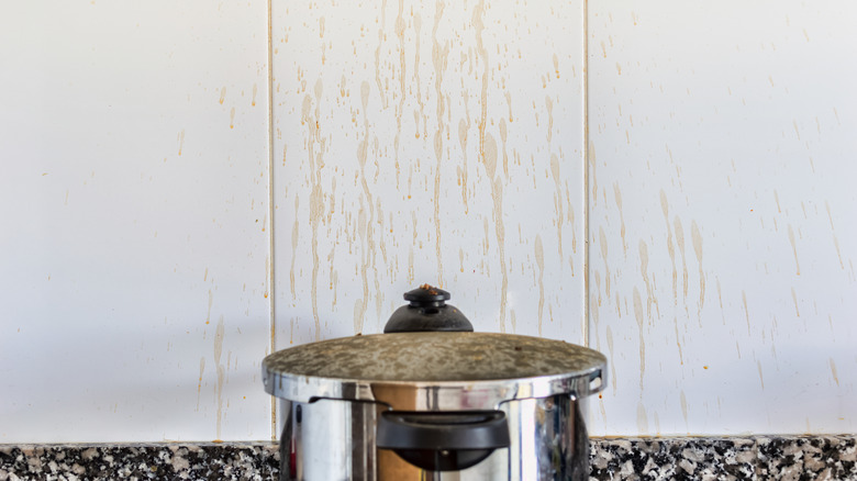 Pot with grease-coated wall behind it in a kitchen