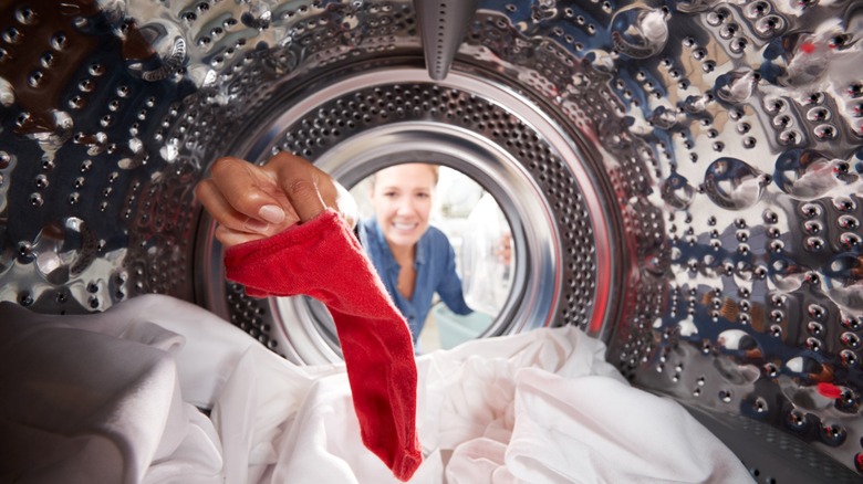 Brightly colored clothes including pink, orange, and red garments inside a front-loading washing machine, showing potential for dye transfer in mixed laundry loads.
