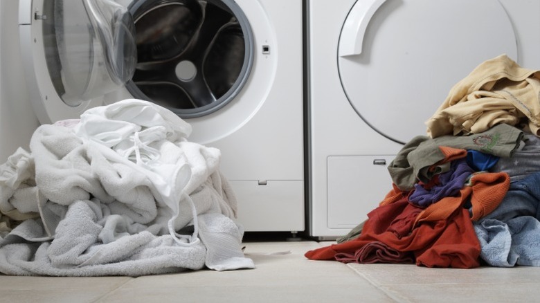 One pile of white clothes and one pile of colored clothes in a laundry room